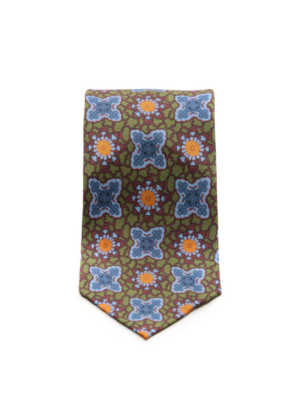 Zbliżenie na front krawata męskiego z zielonego jedwabiu, ozdobionego powtarzalnym wzorem w niebieskie ornamenty i pomarańczowe kwiaty.