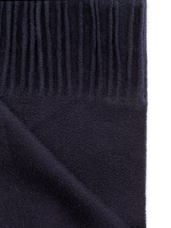 Zbliżenie na strukturę granatowego szala z frędzlami i widoczną fakturą materiału