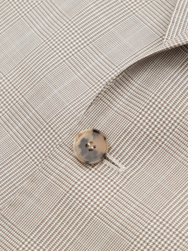 Detal pojedynczego guzika — zbliżenie na główny guzik marynarki; jasny, klasyczny, dopasowany do tkaniny.