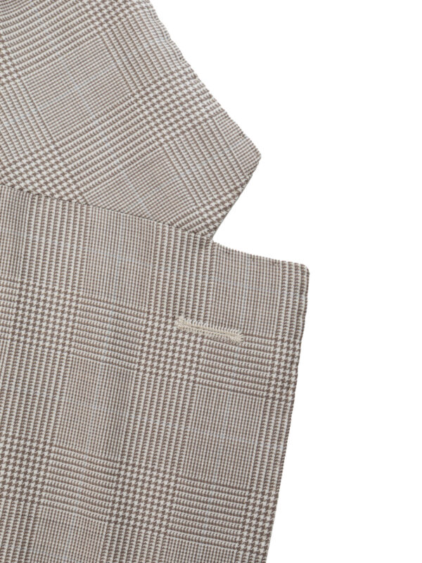 Detal beżowej marynarki męskiej — ręcznie obszyta dziurka na guziki w klapie