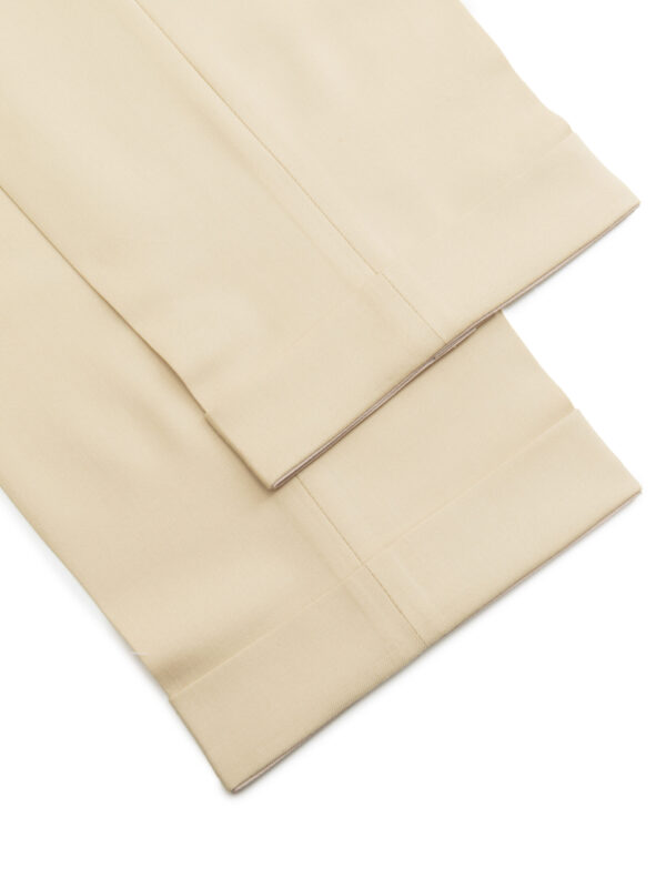 Nogawki beżowych spodni męskich z mankietami, detal starannego wykończenia dołu spodni