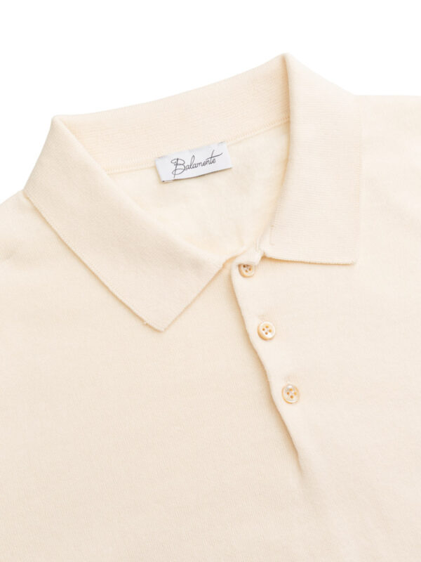 Zbliżenie na kołnierzyk i górną część jasnobeżowej koszulki polo Balamonte z widoczną metką i guzikami.