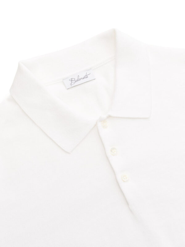 Zbliżenie na kołnierzyk i guziki białej koszulki polo, z widoczną metką Balamonte.