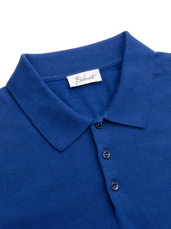 Zbliżenie na niebieski kołnierzyk koszulki polo i guziki — widoczne logo Balamonte na metce.