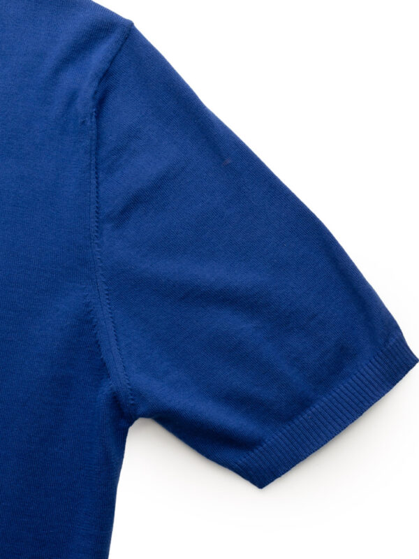 Zbliżenie na rękaw niebieskiej koszulki polo — delikatny ściągacz na mankiecie.