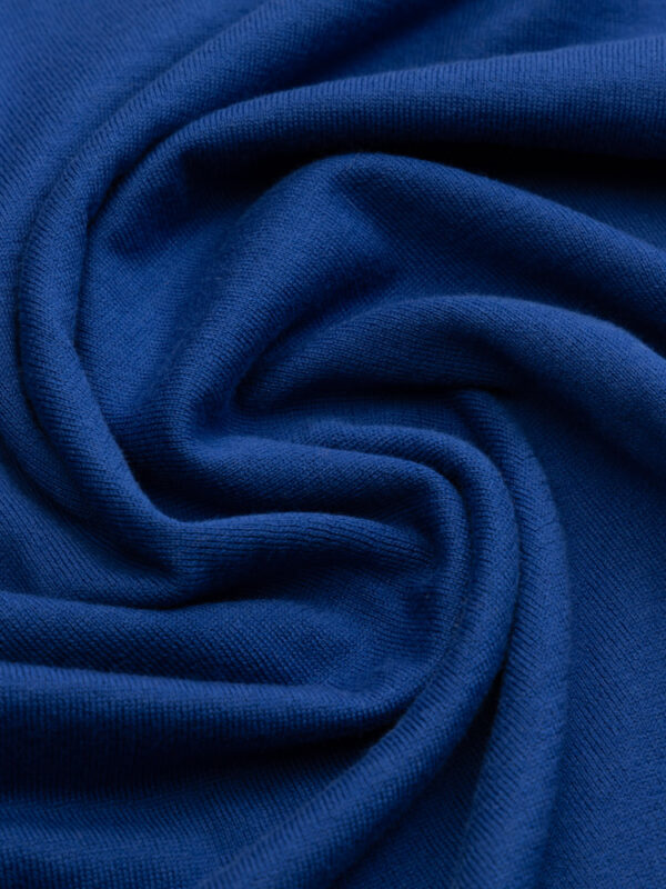 Niebieski materiał koszulki polo w miękkiej, skręconej formie — podkreślenie faktury dzianiny.