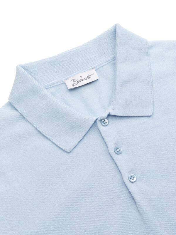 Zbliżenie na kołnierzyk i guziki błękitnej koszulki polo.