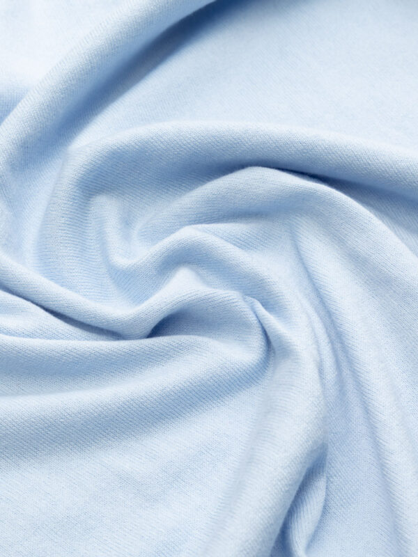 Zbliżenie na materiał błękitnej koszulki polo, pokazujące strukturę dzianiny.