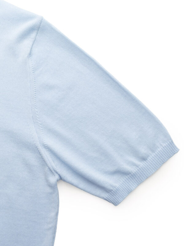 Rękaw błękitnej koszulki polo z widocznym ściągaczem.